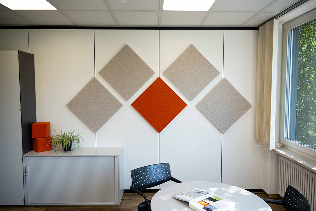 Bright office with a meeting corner and 5 square wall absorbers in greige and orange